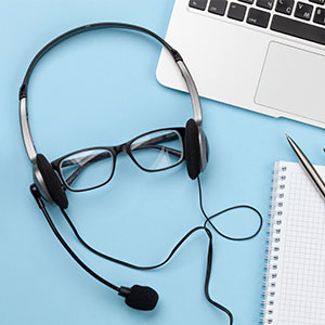 headset and glasses on a blue background with a notebook and laptop suggesting audio communication tools for 5 effective calls