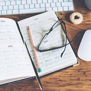 open calendar planner with glasses and pencil next to computer mouse detailed years six month planner