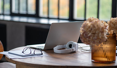 laptop with headphones on wooden table surrounded by flowers and stationery for study or work related to 14 day goals