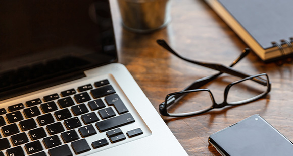 laptop with keyboard on wooden table featuring smartphone glasses and notebook for productivity 2 work tasks