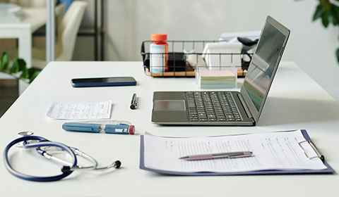 person writing on paper next to laptop with 8 productivity tips and a small cactus on desk