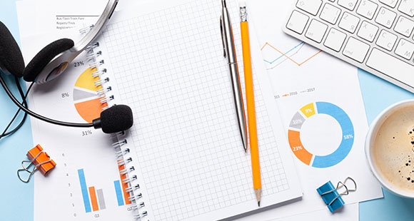 desk with notepad pen headset coffee and charts for analysis and planning processes